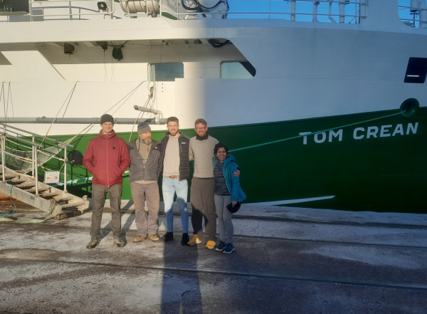 A team of 5 scientists in front of a boat